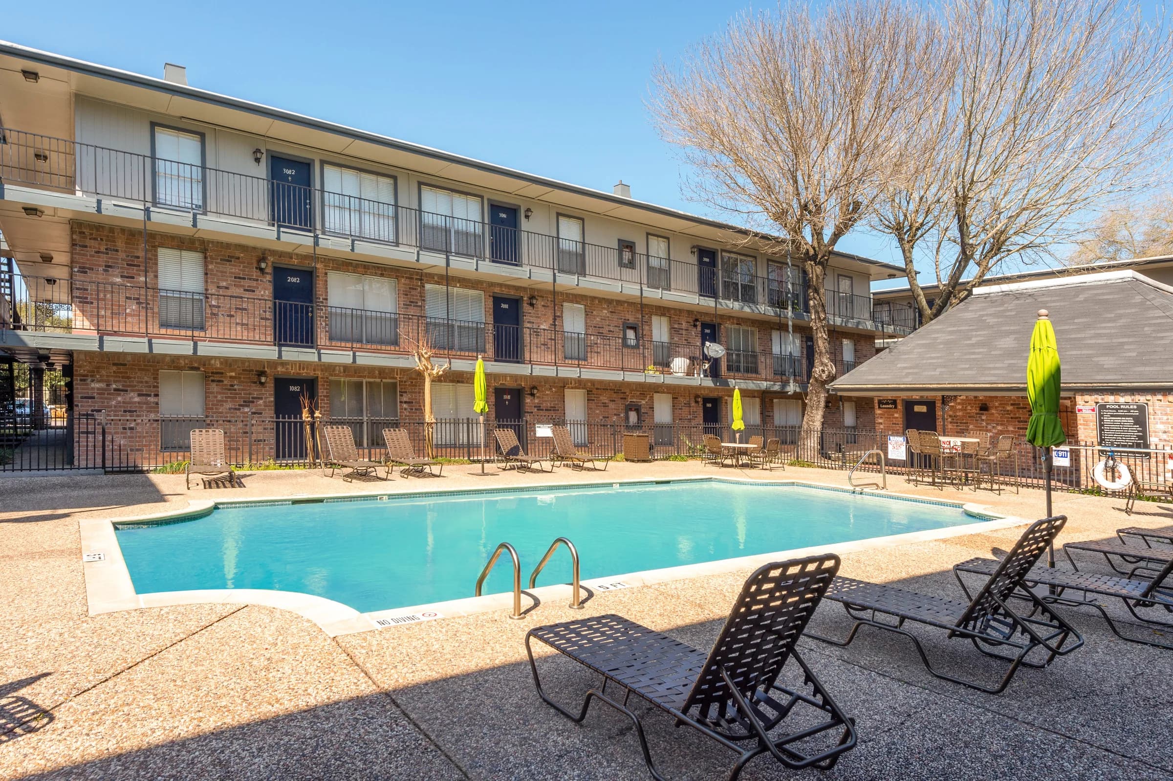 Courtyard pool with lounge chairs, framed by brick buildings